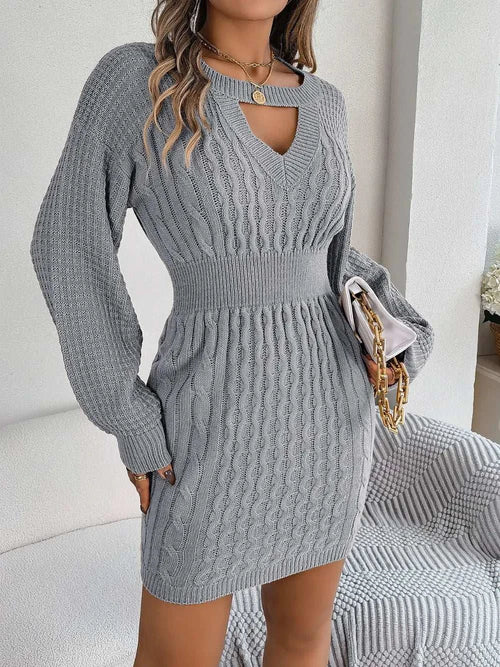 Gray cable-knit cutout sweater dress with round neck and long sleeves, featuring slit and fitted waist detail