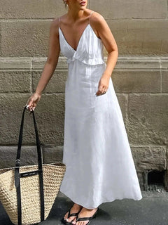 Woman wearing white ruffled V-neck maxi dress with thin straps carrying a large woven tote bag