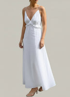 Woman wearing white ruffled V-neck maxi dress with thin straps carrying a large woven tote bag