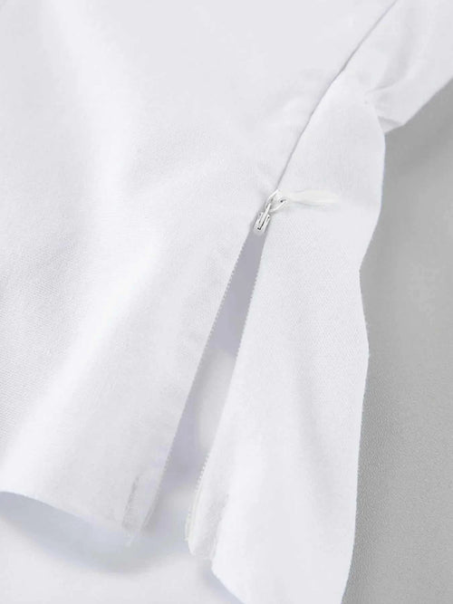 Close-up of white cotton fabric with a hidden zipper detail on a ruffled V-neck maxi dress