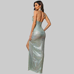 Woman wearing mint green Mackenzie Cut Out halter gown with backless and slit design against dark wall