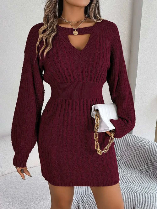 Woman wearing a burgundy cable-knit cutout round neck slit sweater dress with long sleeves and a fitted waist holding a white purse with gold chain strap