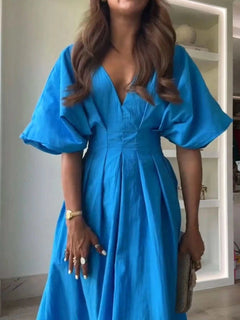 Woman wearing a blue V-neck half sleeve midi dress with ruched detail and backless design