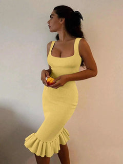 Yellow ribbed knit bodycon dress with sleeveless design and ruffle hem detail worn by woman holding an orange