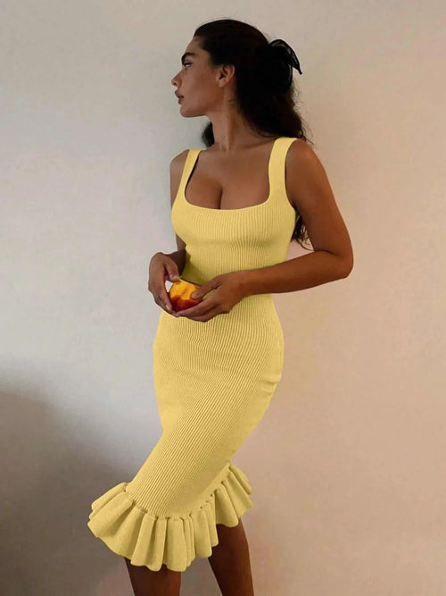 Yellow ribbed knit bodycon dress with sleeveless design and ruffle hem detail worn by woman holding an orange