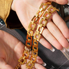 Gold-plated titanium steel chain bracelet with hollow square links held in hand