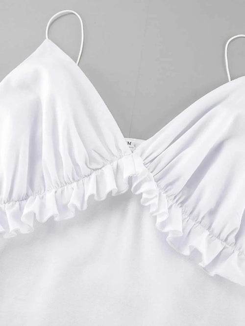 Close-up of white ruffled V-neck maxi dress with frill detail and thin straps made of 100% cotton.