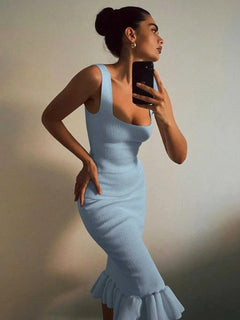 Woman wearing a light blue ribbed knit bodycon dress with a ruffle hem taking a mirror selfie