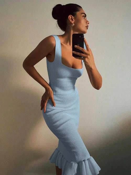 Woman wearing a light blue ribbed knit bodycon dress with a ruffle hem taking a mirror selfie