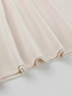 Close-up of cream asymmetrical tied sleeveless maxi dress fabric hem detail
