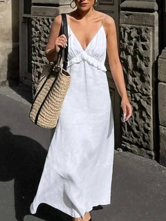 Woman wearing white ruffled V-neck maxi dress carrying straw bag on city street