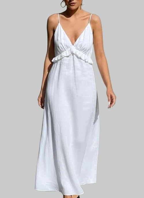 Woman wearing white ruffled V-neck maxi dress carrying straw bag on city street