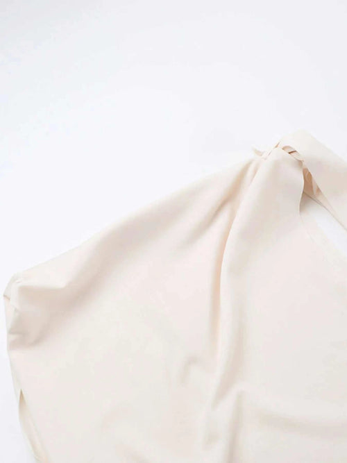 Close-up of an asymmetrical tied sleeveless maxi dress in soft beige polyester fabric