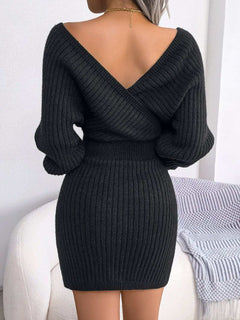 Back view of a woman wearing a black rib-knit dolman sleeve sweater dress with a surplice neckline and A-line mini hem.