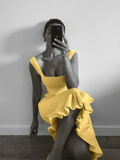 Woman wearing yellow ribbed knit bodycon dress with ruffle hem taking mirror selfie