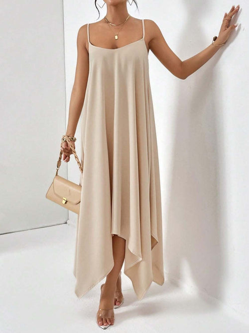Beige scoop neck midi cami dress with handkerchief hem and spaghetti straps worn with nude heels and matching handbag.