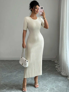 Woman wearing a ribbed round neck short sleeve white sweater dress with moderate stretch, holding a white handbag and taking a mirror selfie