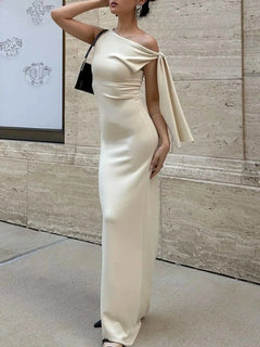 Cream asymmetrical tied sleeveless maxi dress with a fitted silhouette and elegant draped shoulder detail