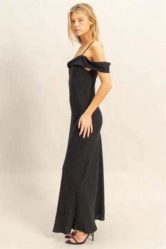 Woman wearing a black HYFVE Flattering Fit Cami Maxi Dress with asymmetrical ruffled neckline and slim fit silhouette.