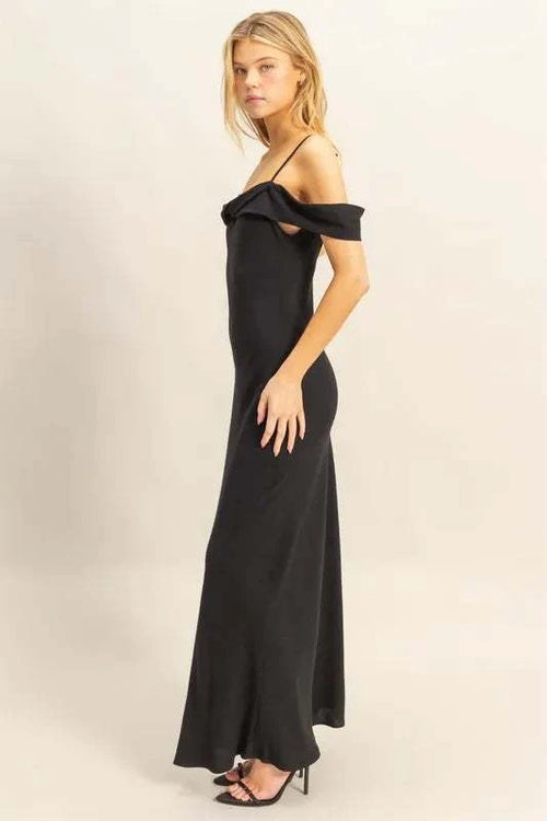 Woman wearing a black HYFVE Flattering Fit Cami Maxi Dress with asymmetrical ruffled neckline and slim fit silhouette.