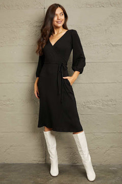 Culture Code Full Size black surplice flare midi dress with ruching sleeves and waist tie worn with white boots