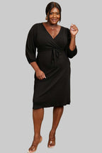 Culture Code Full Size black surplice flare midi dress with ruching sleeves and waist tie detail worn by plus-size model