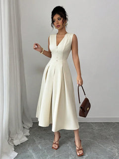 Woman wearing V-neck sleeveless midi dress in cream with buttoned front and pleated skirt holding brown handbag