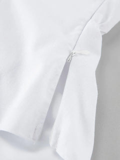 Close-up of white cotton fabric with a hidden zipper detail on a ruffled V-neck maxi dress
