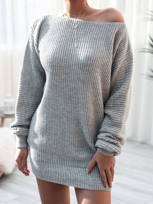 Woman wearing gray rib-knit mini sweater dress with off-shoulder neckline and long sleeves in bright indoor setting