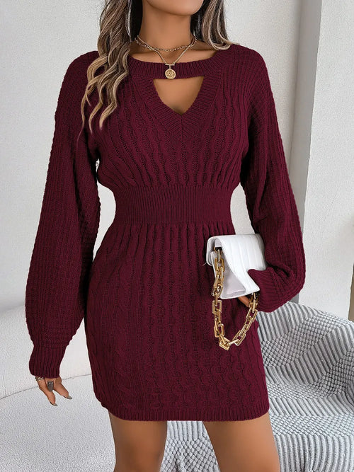 Woman wearing a burgundy cable-knit cutout round neck slit sweater dress with long sleeves and a fitted waist holding a white purse with gold chain strap