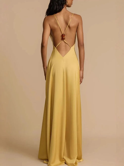 Back view of a yellow deep V-neck maxi dress with backless and crisscross strap design.