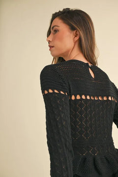Long sleeve tiered ruffle knit midi dress in black with intricate cable-knit details and cutout design.