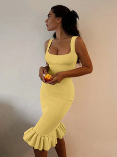 Yellow ribbed knit bodycon dress with sleeveless design and ruffle hem detail worn by woman holding an orange