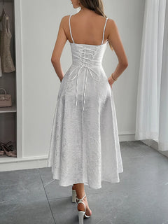 Back view of a white lace-up sleeveless midi dress with ruched detailing and lined polyester fabric worn with high-heeled sandals in a modern interior setting