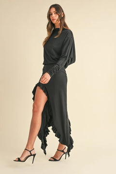 Woman wearing black Mable Backless Asymmetric Ruffle Hem Dress with high slit and ruffle details