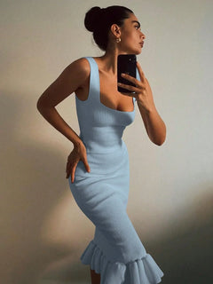 Woman wearing a light blue ribbed knit bodycon dress with a ruffle hem taking a mirror selfie