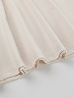 Close-up of cream asymmetrical tied sleeveless maxi dress fabric hem detail