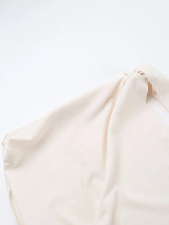 Close-up of an asymmetrical tied sleeveless maxi dress in soft beige polyester fabric
