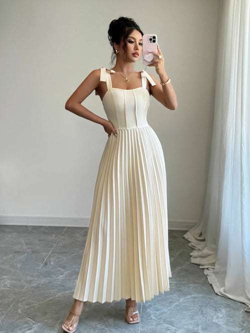 Woman wearing white pleated tie-shoulder maxi dress with bow details and square neckline