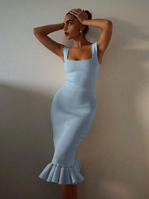 Woman wearing light blue ribbed knit bodycon dress with square neckline and ruffle hem standing against plain background