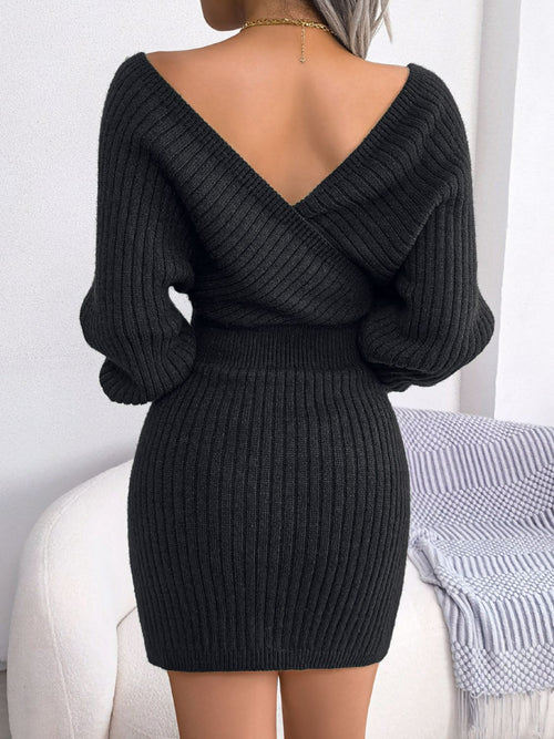 Back view of a woman wearing a black rib-knit dolman sleeve sweater dress with a surplice neckline and A-line mini hem.