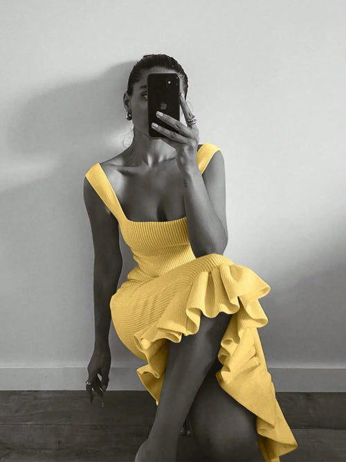 Woman wearing yellow ribbed knit bodycon dress with ruffle hem taking mirror selfie