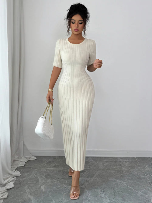 White ribbed round neck short sleeve sweater dress with moderate stretch, midi length, worn with white handbag and clear heels