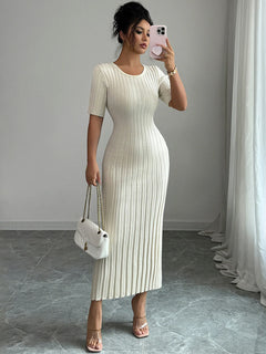 Woman wearing a ribbed round neck short sleeve white sweater dress with moderate stretch, holding a white handbag and taking a mirror selfie