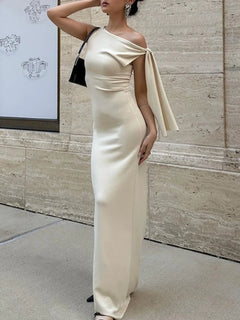 Cream asymmetrical tied sleeveless maxi dress with a fitted silhouette and elegant draped shoulder detail