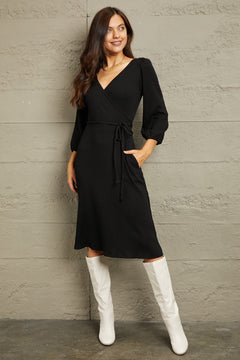Culture Code Full Size black surplice flare midi dress with ruching sleeves and waist tie worn with white boots