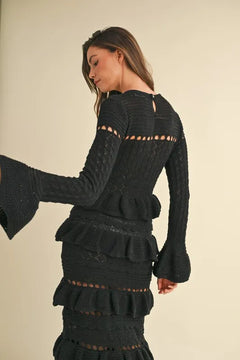 Long sleeve tiered ruffle knit midi dress in black with cable-knit design and cutout details.