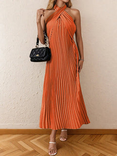 Orange pleated halter neck midi dress with tied detail and no stretch, styled with a black quilted handbag and beige heels
